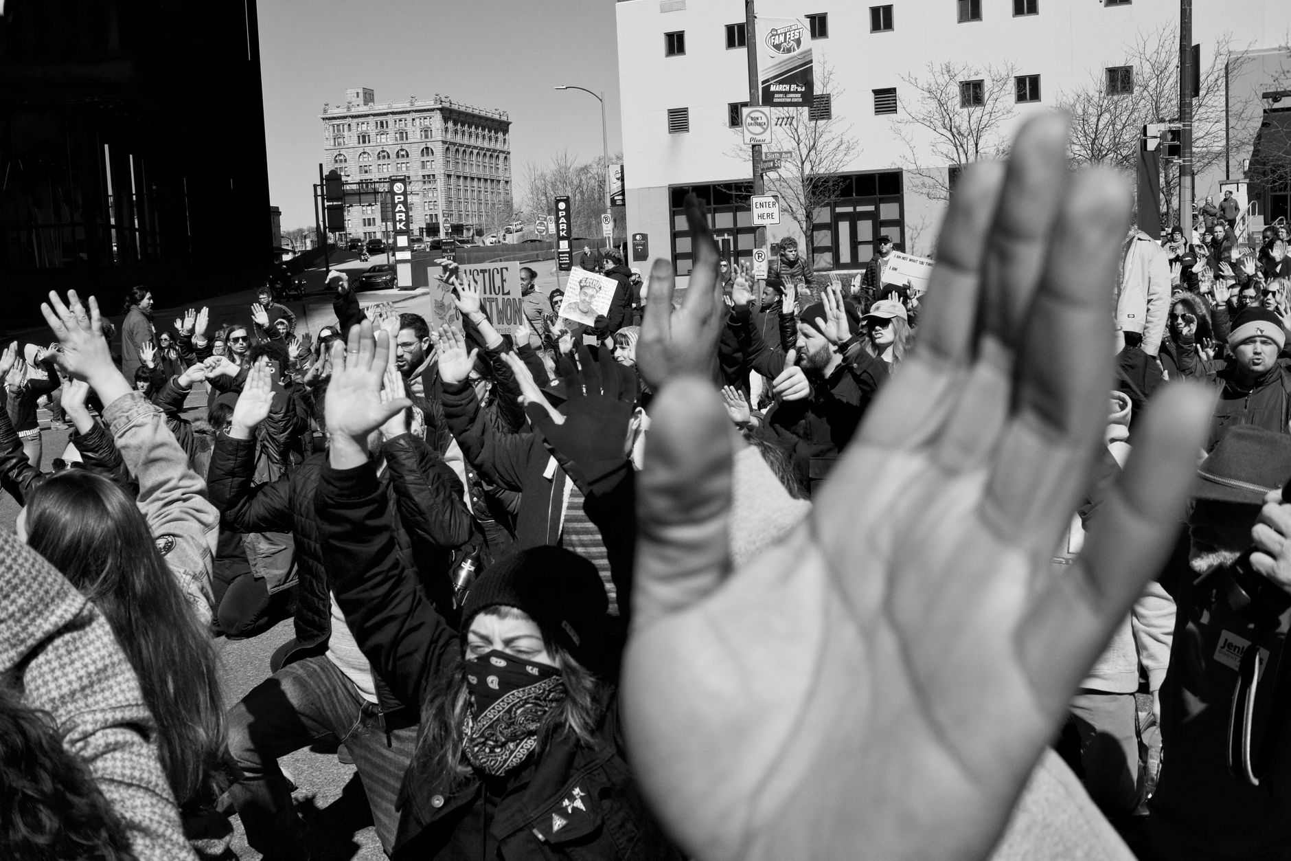 Black and white photo of a street protest with raised hands and diverse individuals.