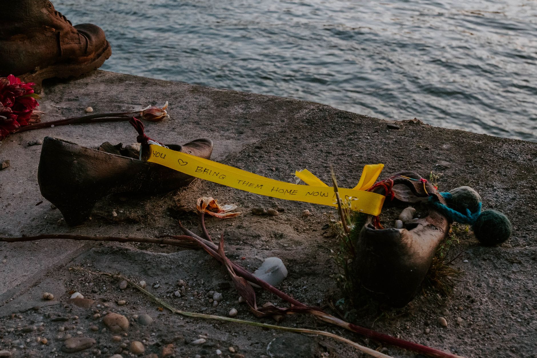 A moving memorial on the Danube riverbank in Budapest with shoes and a heartfelt message.