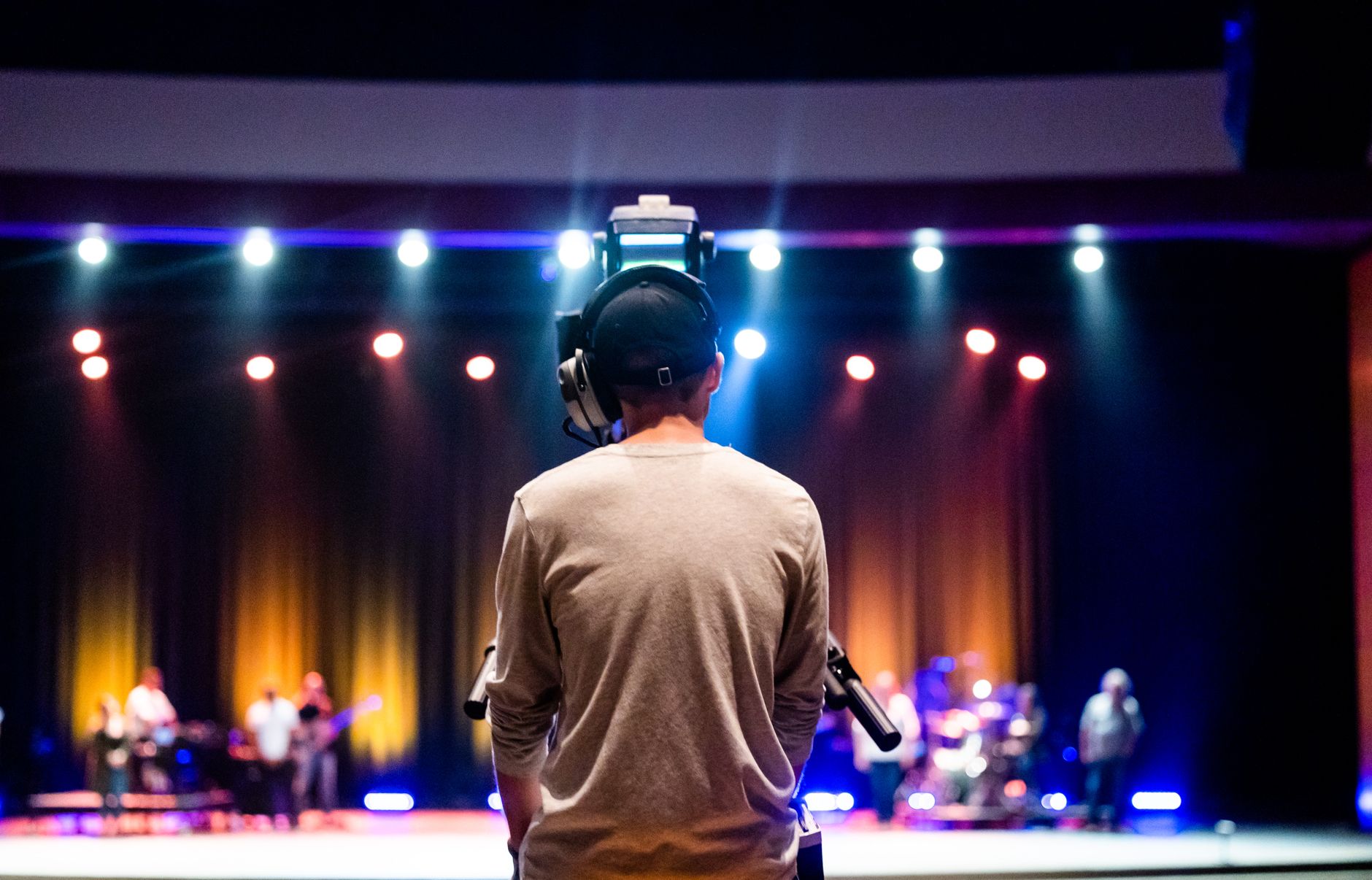 Back view of a camera operator capturing a live concert on stage.