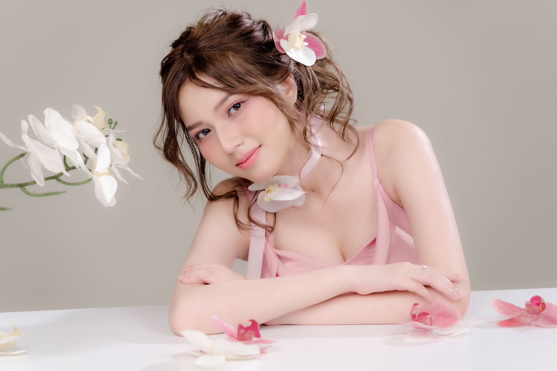 A serene portrait of a woman adorned with orchids, smiling softly.