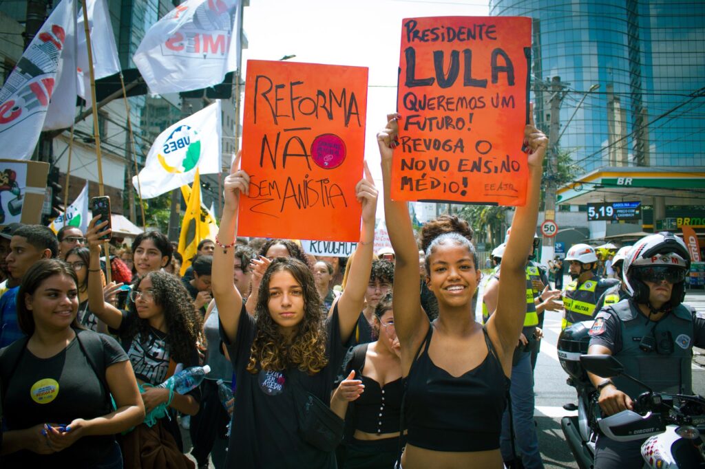 Youth-led street protest with signs advocating educational reform and political change.