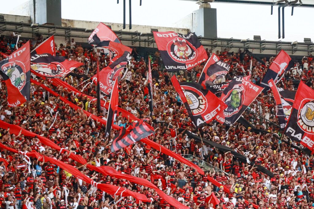 A lively crowd of Flamengo supporters waving flags at Maracanã Stadium in Rio de Janeiro.