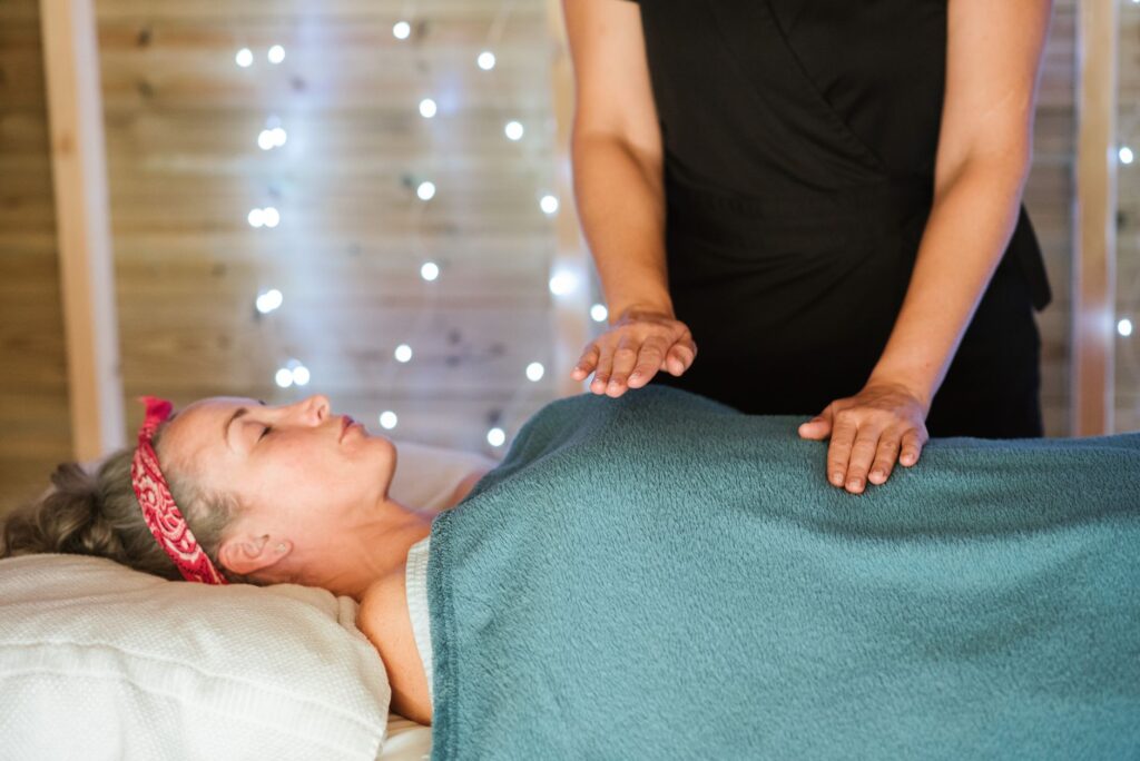 Adult woman resting on comfortable bed in towel while having massage in spa salon