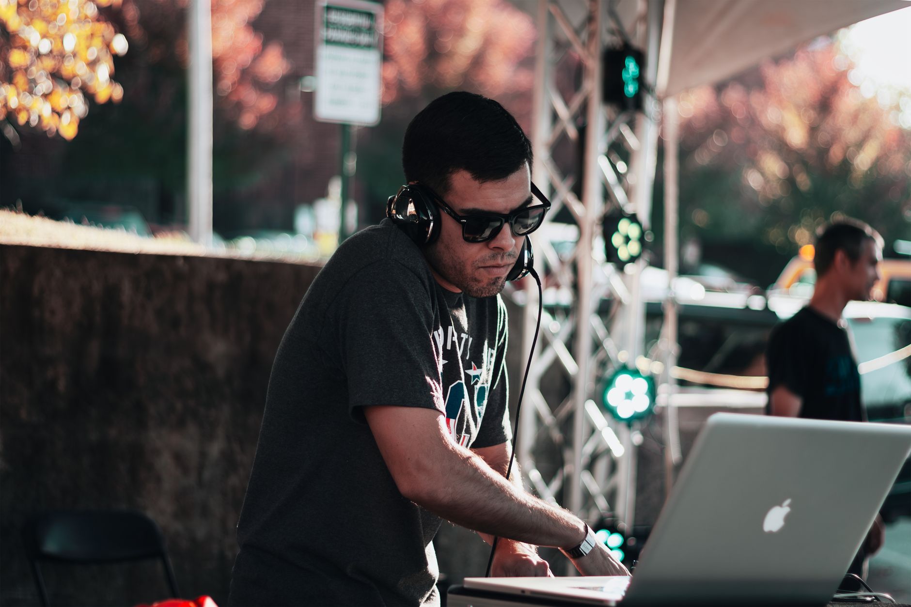 DJ performing outdoors in Fayetteville, AR using a laptop and headphones.