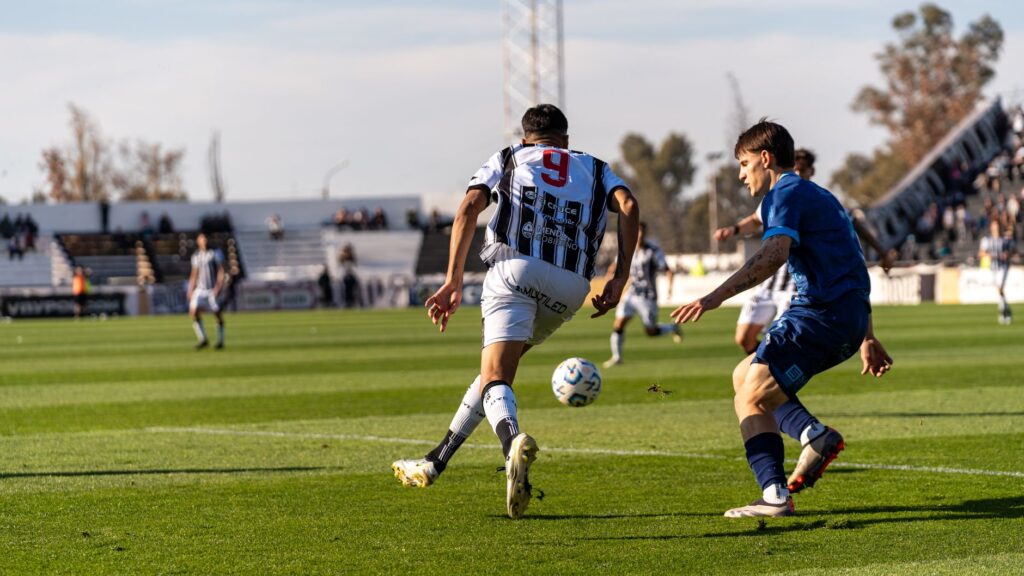 Players in action on the soccer field during an outdoor match under the bright sun.