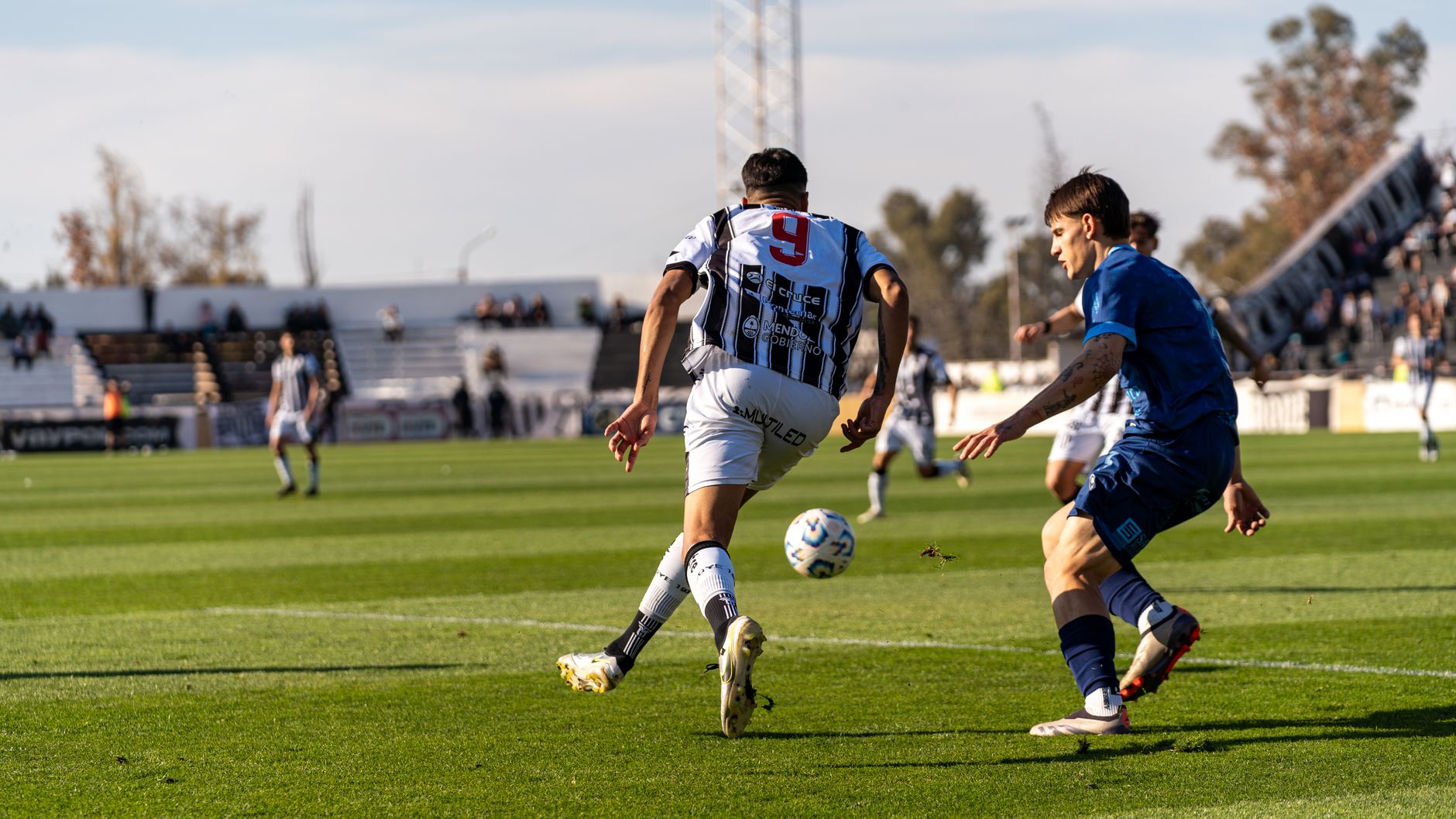 Players in action on the soccer field during an outdoor match under the bright sun.