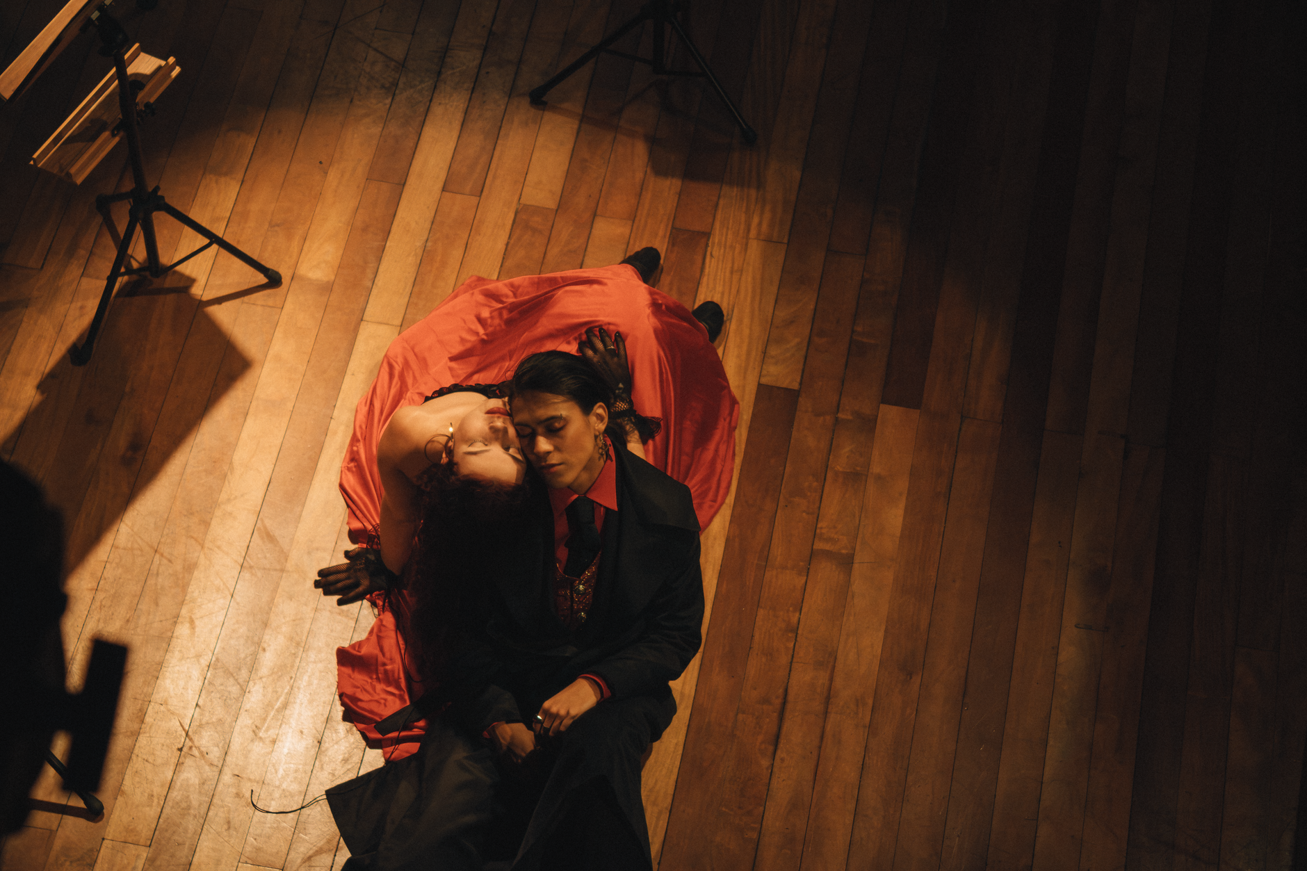 Overhead view of an elegant couple in dramatic attire resting on a wooden floor.
