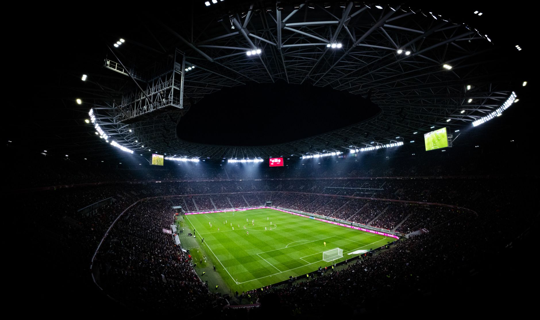 Aerial view of a night football match in Budapest. Illuminated stadium full of fans adds dramatic atmosphere.