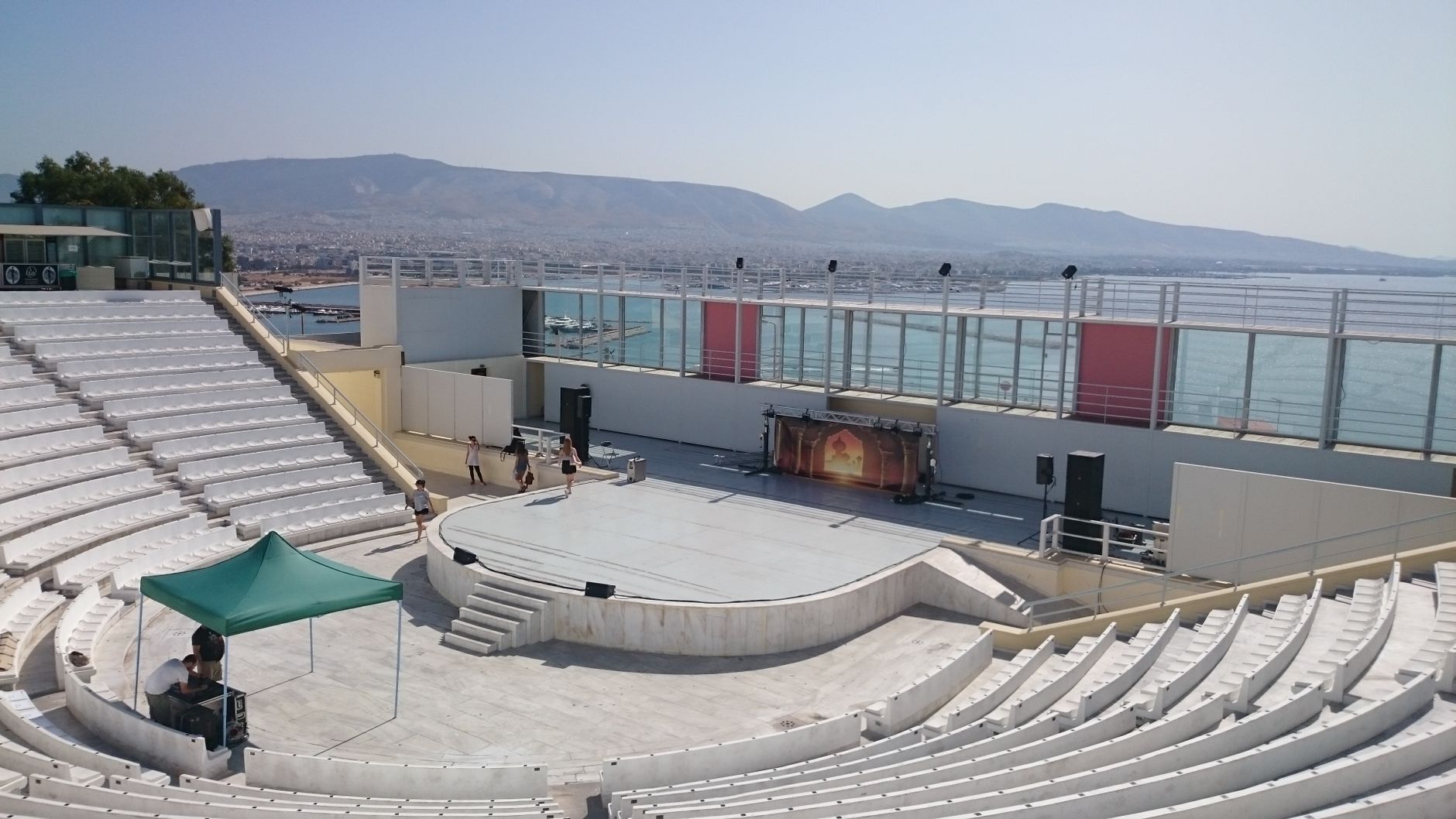 Amphitheater with stage setup by the sea, vibrant outdoor ambiance.
