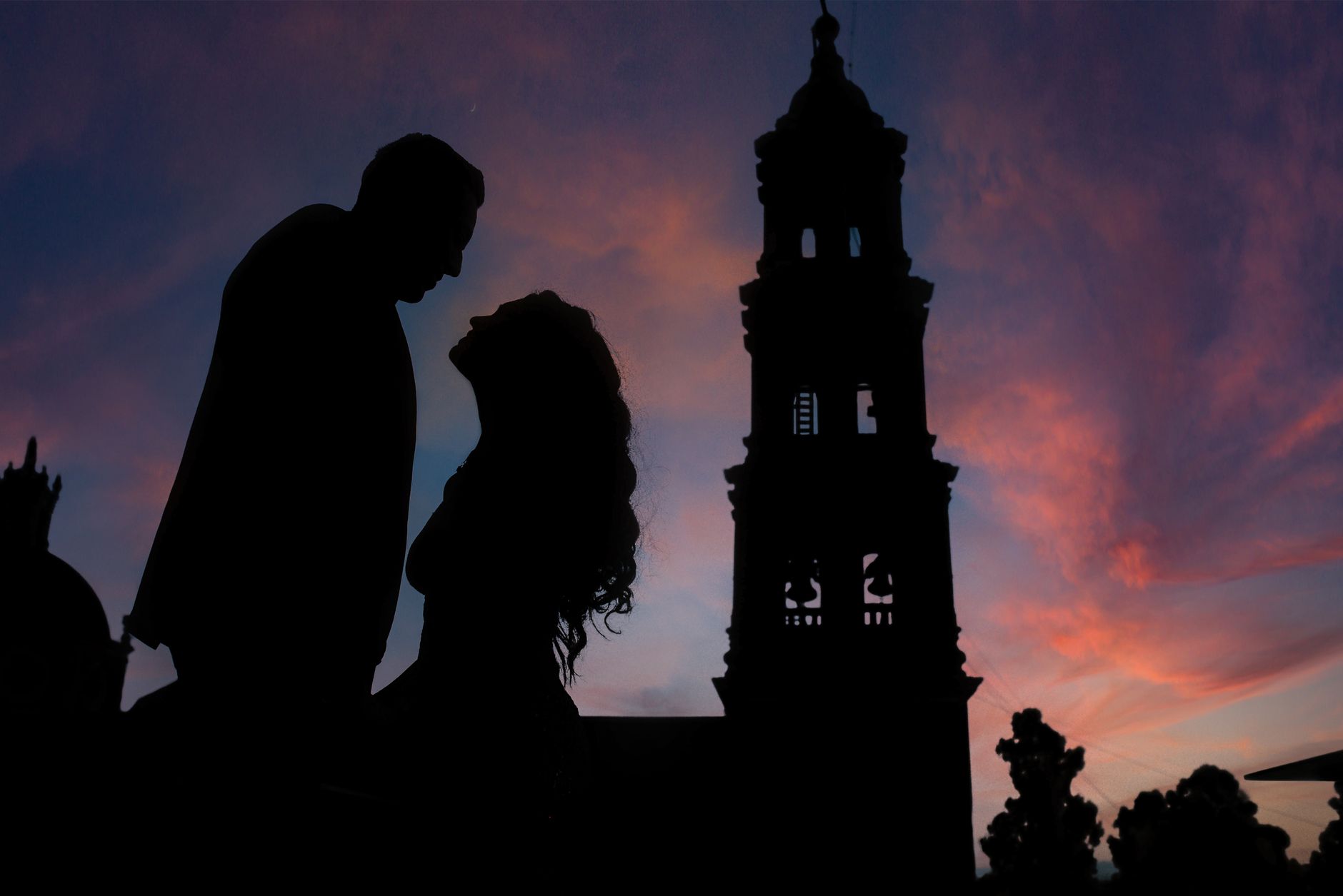 Silhouette of a couple at sunset with Guanajuato church backdrop.