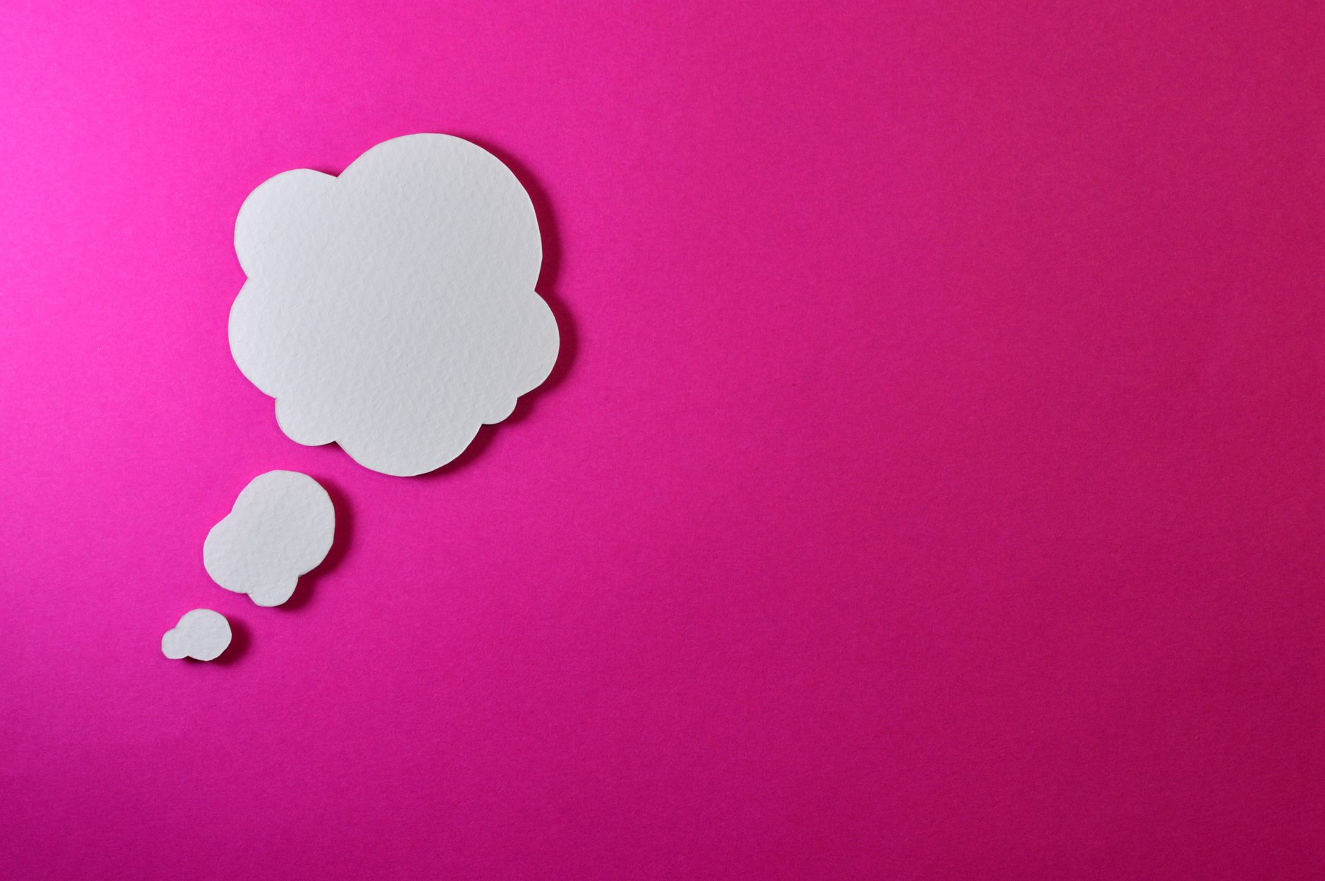 Paper thought bubble over bright pink background, ideal for creative concepts.
