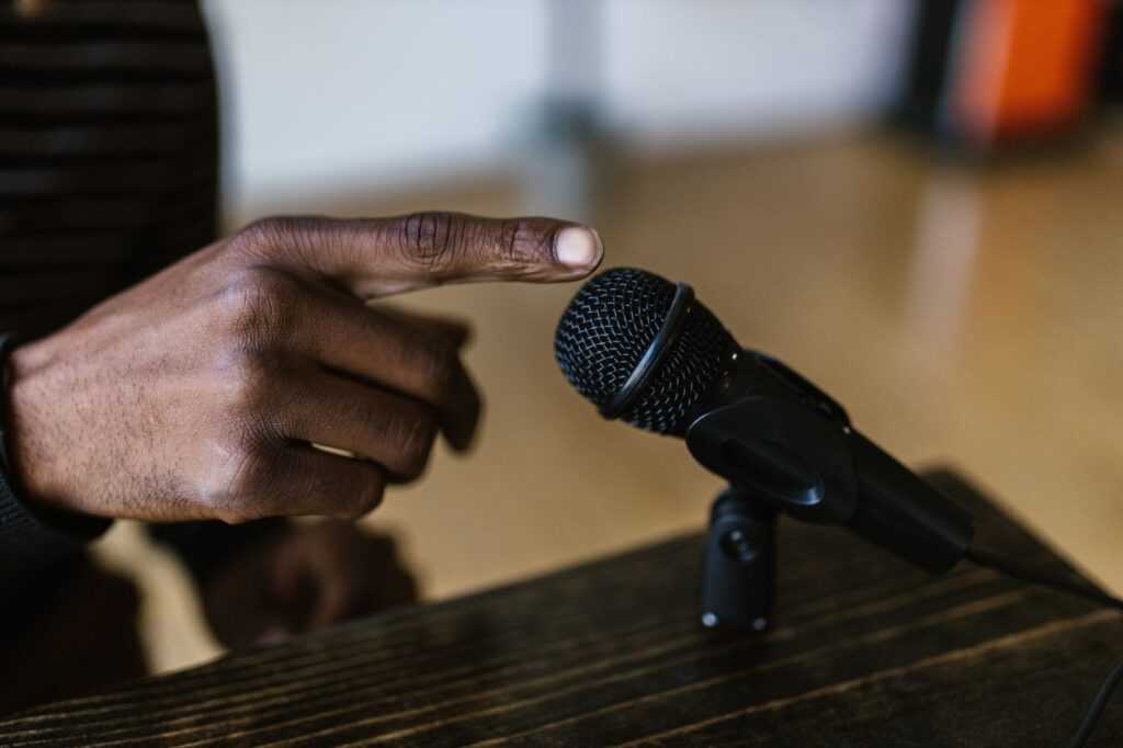 Close-up shot of a hand touching a microphone, ideal for audio, podcast themes.