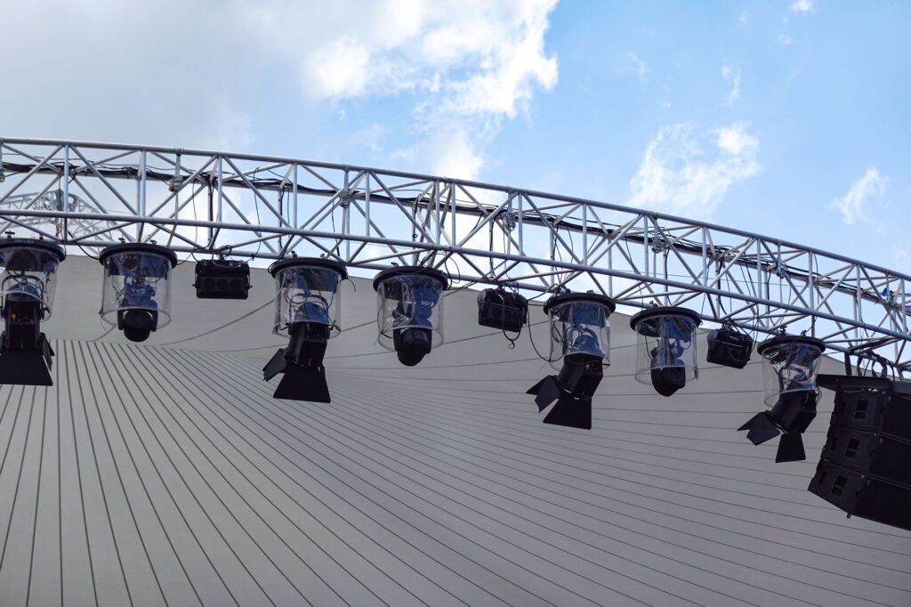 Overhead view of an outdoor stage with modern lighting setup against a blue sky.