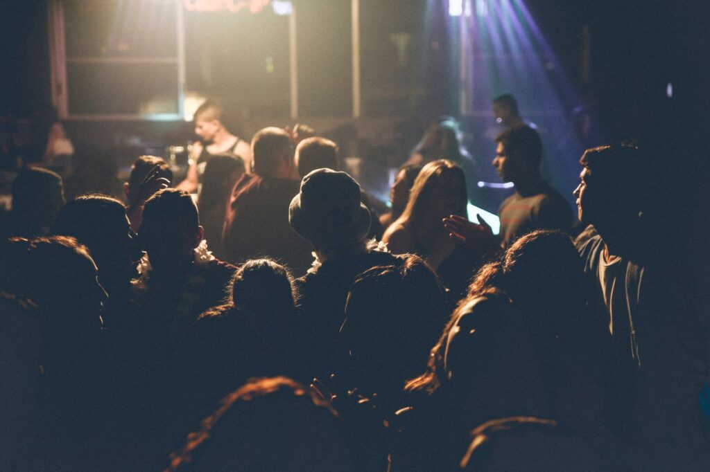 A lively crowd enjoying a concert with soft lighting and performers on stage.
