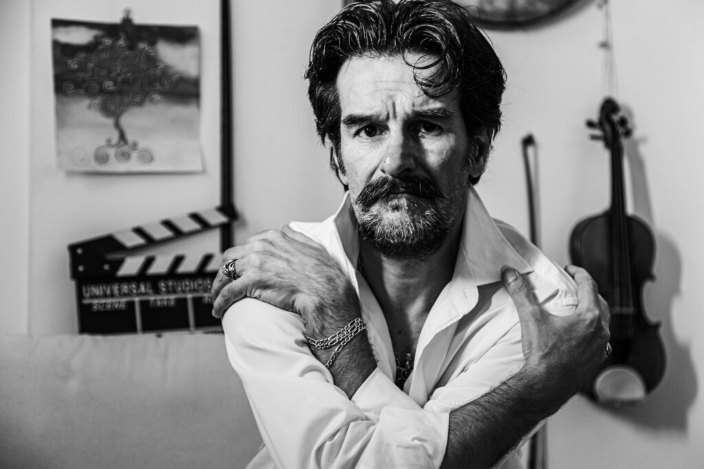 Emotionally compelling black and white portrait of a man with a violin in the background.