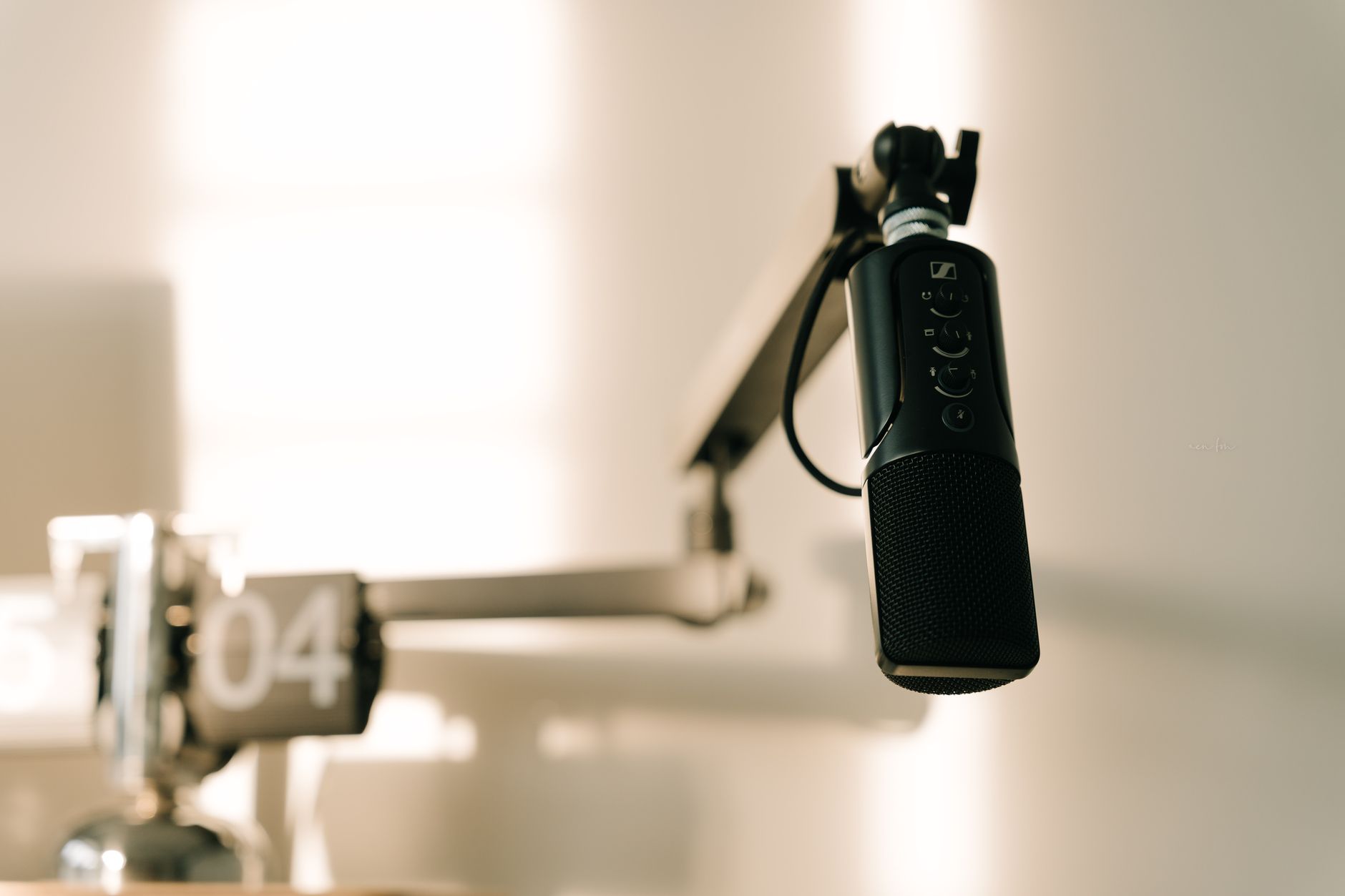 A sleek professional microphone on a boom arm in a minimalist studio.